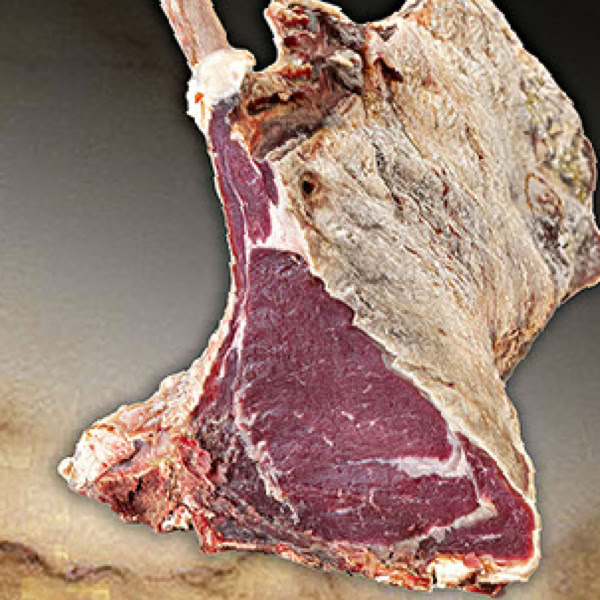 Ein gro&szlig;es rohes Tamahawk-Steak mit Knochen auf einem dunklen Hintergrund.