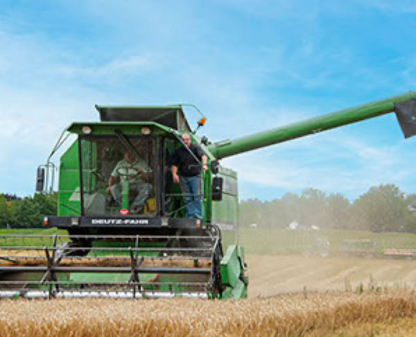 Gr&uuml;ner M&auml;hdrescher erntet ein Feld unter blauem Himmel.