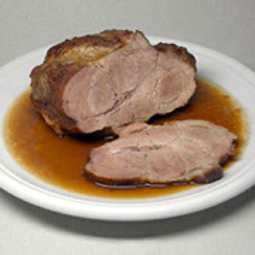 Ein Teller mit zwei Scheiben Schweinebraten in So&szlig;e.